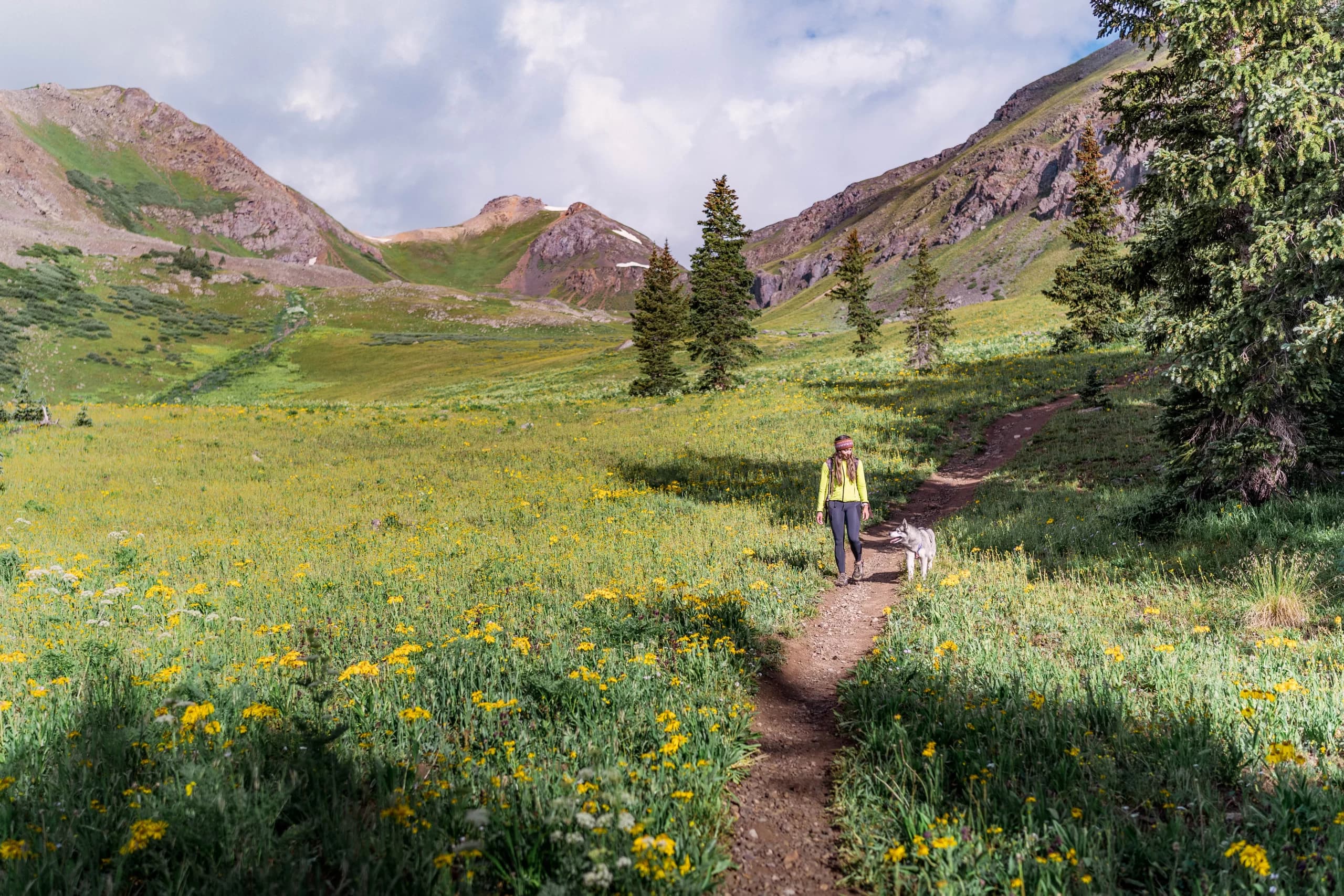 Dog trainer walking with husky on mountain trail